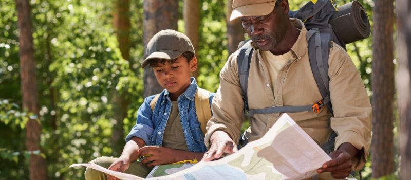 Older man showing male child how to read a map