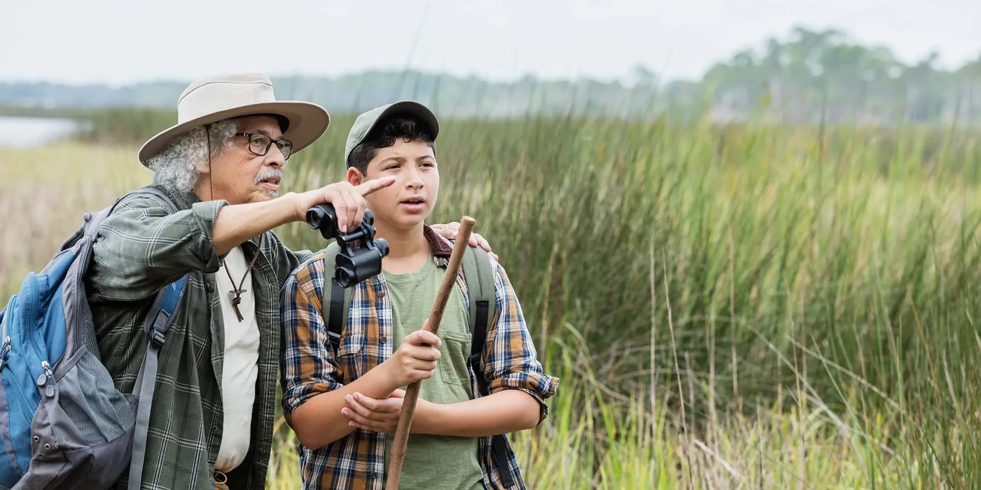 Older man with younger boy experience wetlands in a park.
