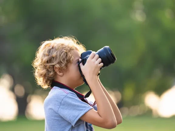 Small boy taking a photo in nature with camera