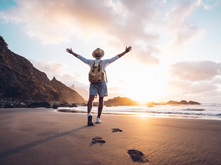 Person raises arms on beach