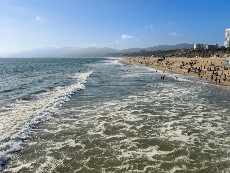 Visitors relax and explore Santa Monica State Beach, with sweeping views of the Pacific Ocean, sandy shoreline, and the Los Angeles coastline in the distance.