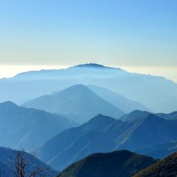california mountains fading into the distance with blue sky above and warm mountain forest in the foreground