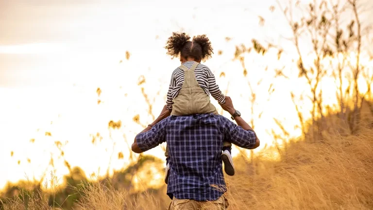 Child on shoulders hiking