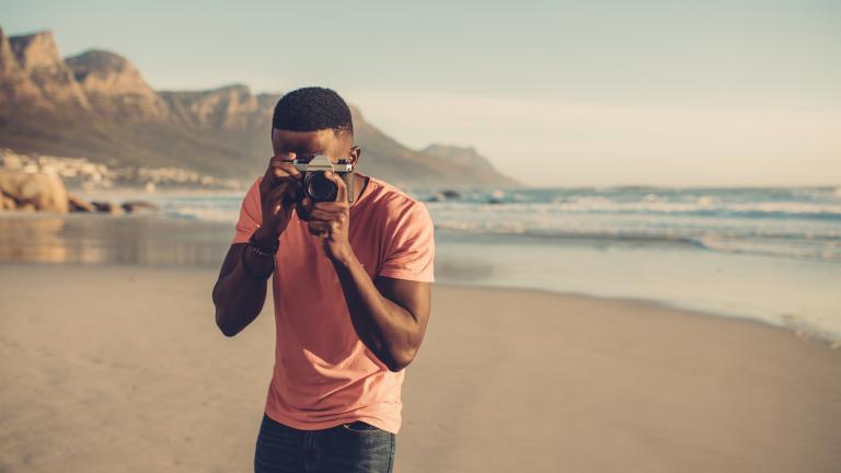 Man with camera taking photo on beach