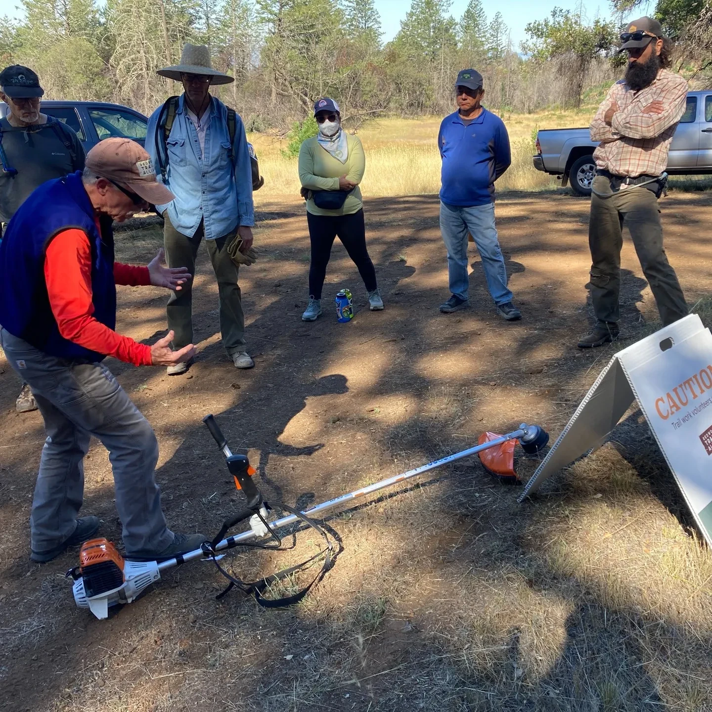 A group of volunteers getting instruction from a team leader outdoors